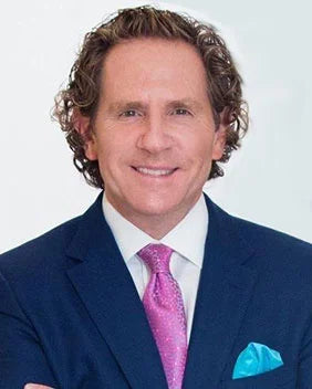 Man wearing a blue suit with a pink tie and blue handkerchief on a white background