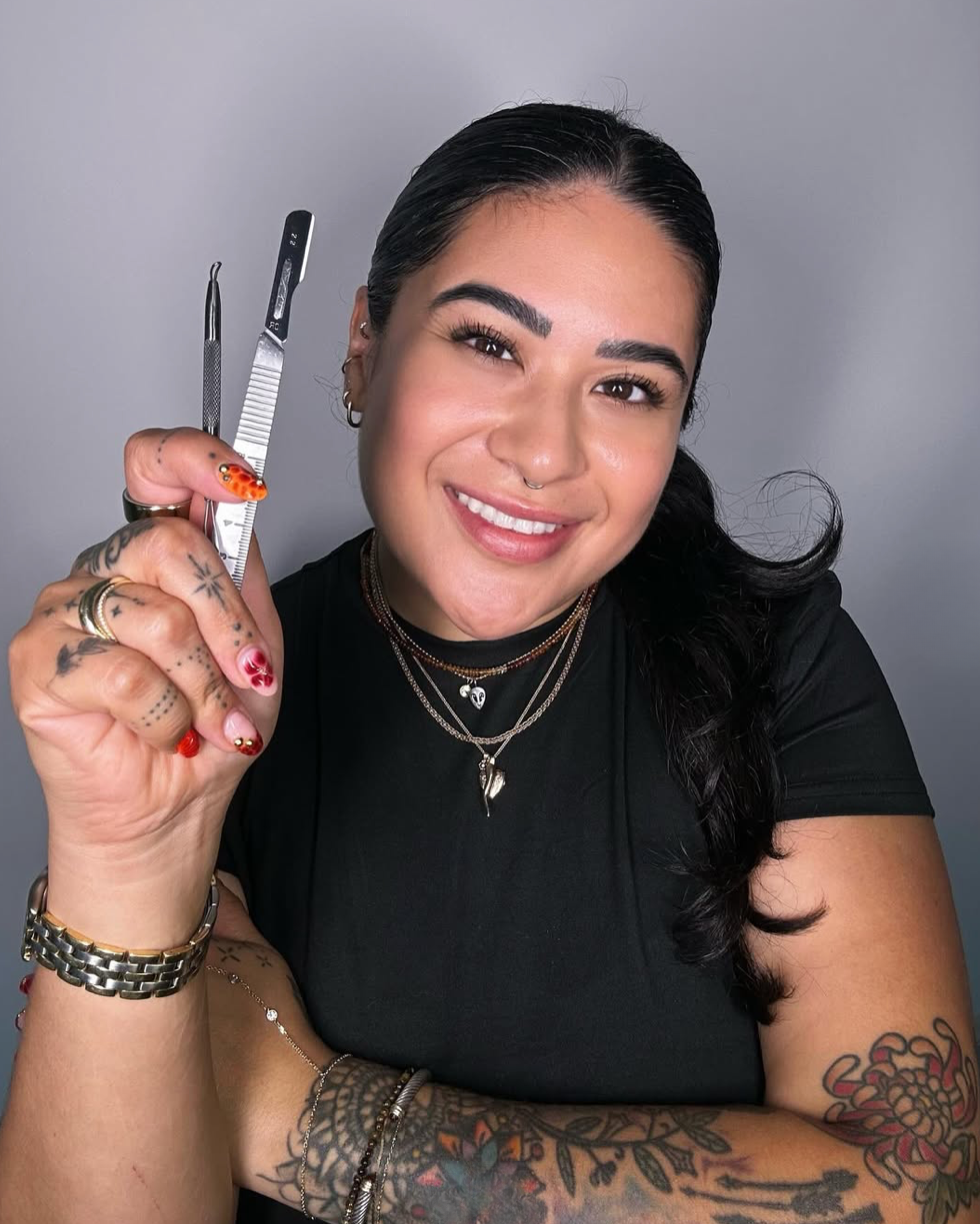 Person holding a pair of scissors against a gray background