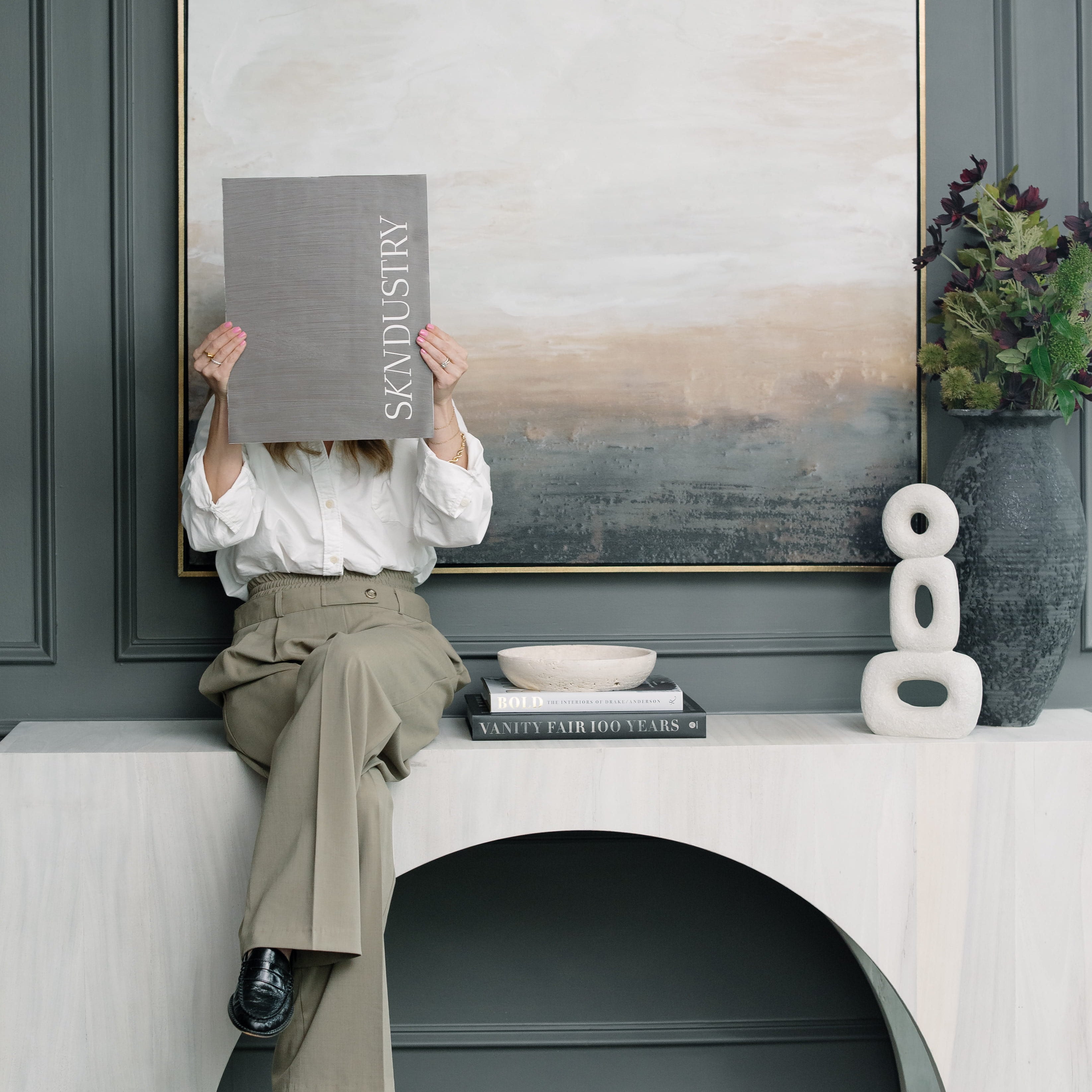 Person sitting on a white bench in a modern interior setting of one of the best med spas in philadelphia with a large abstract painting on the wall.