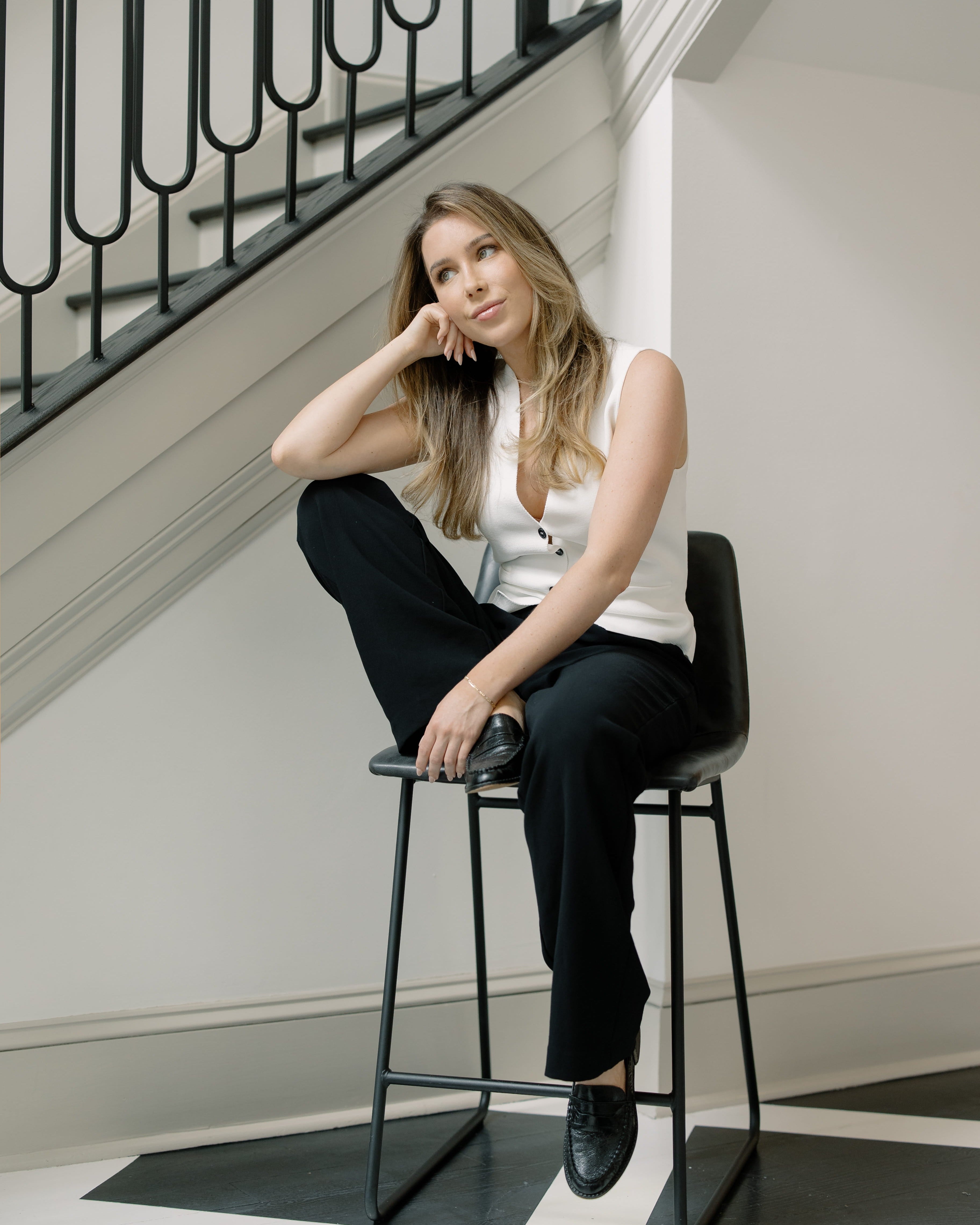 Kaitlyn Nelson, owner of a boutique med spa in philadelphia, sitting on a black stool in a modern interior setting.