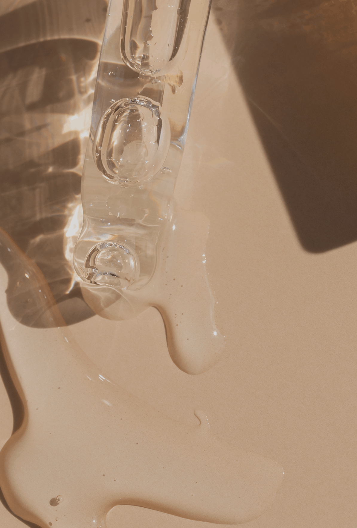 Clear glass bottle with a regenerative skincare dropper on a beige surface